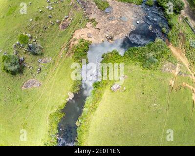 Luftaufnahme von Farm Field, Bäumen und Bach mit Wasserfall in Sao Francisco de Paula, Rio Grande do Sul, Brasilien Stockfoto