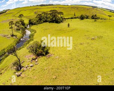 Luftaufnahme von Farm Field, Wald und Bach mit Wasserfall in Sao Francisco de Paula, Rio Grande do Sul, Brasilien Stockfoto