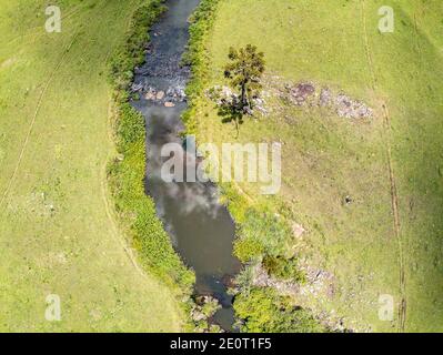 Luftaufnahme von Farm Field, Wald und Bach mit Wasserfall in Sao Francisco de Paula, Rio Grande do Sul, Brasilien Stockfoto