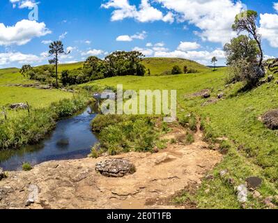 Farm Feld, Bäume und Bach mit Wasserfall in Sao Francisco de Paula, Rio Grande do Sul, Brasilien Stockfoto