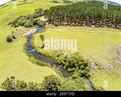 Luftaufnahme von Farm Field, Wald und Bach mit Wasserfall in Sao Francisco de Paula, Rio Grande do Sul, Brasilien Stockfoto