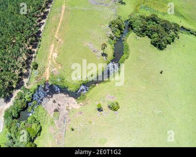 Luftaufnahme von Farm Field, Wald und Bach mit Wasserfall in Sao Francisco de Paula, Rio Grande do Sul, Brasilien Stockfoto