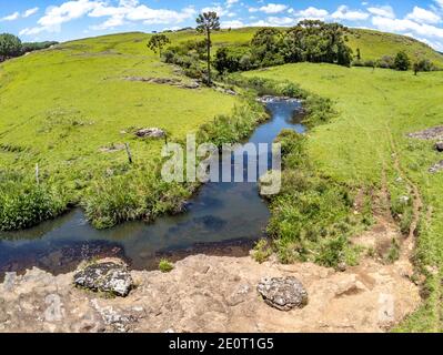 Farm Feld, Bäume und Bach mit Wasserfall in Sao Francisco de Paula, Rio Grande do Sul, Brasilien Stockfoto