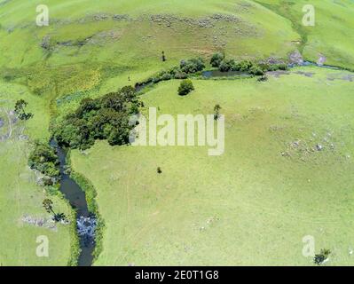 Luftaufnahme von Farm Field, Wald und Bach mit Wasserfall in Sao Francisco de Paula, Rio Grande do Sul, Brasilien Stockfoto