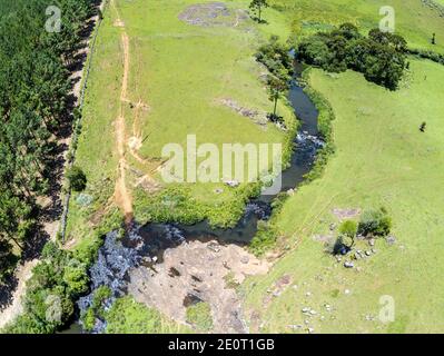 Luftaufnahme von Farm Field, Wald und Bach mit Wasserfall in Sao Francisco de Paula, Rio Grande do Sul, Brasilien Stockfoto