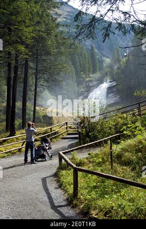 Ein Mann mit Kinderwagen blickt auf die Krimmler Wasserfälle, den höchsten Wasserfall Österreichs. Stockfoto