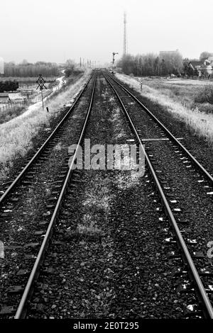 Zwei Bahngleise, die durch die Felder führen. Bahntraktion in der Nähe des Bahnhofs. Wintersaison. Stockfoto