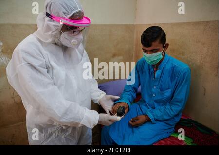 Inmitten der Coronavirus-Pandemie, die im Land rasch ansteigt, in voller PSA-Ausrüstung gekleidet, diagnostiziert Dr. Saeed-ur-Rehman einen Patienten in seiner Klinik im Nachbarort Shiri Jinnah in Karachi, der wichtigsten Hafenstadt Pakistans. Stockfoto