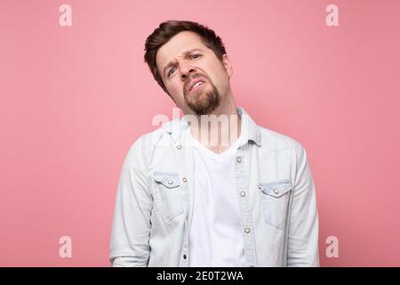 Schöner Mann mit Bart ist gelangweilt Blick auf die Kamera. Studio auf rosa Wand aufgenommen. Stockfoto