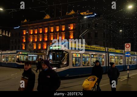 Paradeplatz in der weihnachtszeit bei Nacht. Beleuchtete Fenster des Hauptquartiers von Banken und Straßenbahnhaltestelle in Zürich mit vielen Hängelampen namens Lucy. Zur Stockfoto