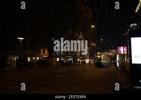 Blick auf den Hauptbahnhof zürich und die Bahnhofstrasse zur Weihnachtszeit in der Zeit des Corona Virus. Hängelampen namens Lucy, Fußgänger- und Straßenbahnweg Stockfoto