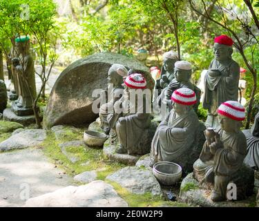 Statuen der ursprünglichen Anhänger Buddhas (Shaka Nyorai in Japan" genannt), mit gestrickten Mützen an Daisho-in Tempel (Daishoin Tempel), Miyajima, Japan. Stockfoto