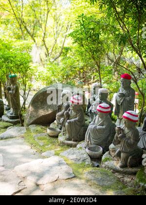 Statuen der ursprünglichen Anhänger Buddhas (Shaka Nyorai in Japan" genannt), mit gestrickten Mützen an Daisho-in Tempel (Daishoin Tempel), Miyajima, Japan. Stockfoto