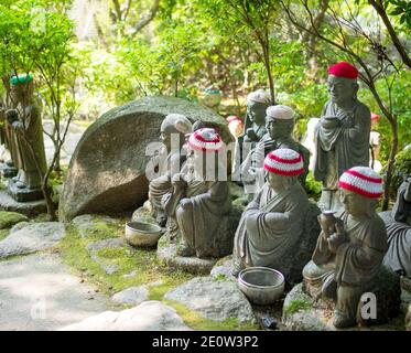 Statuen der ursprünglichen Anhänger Buddhas (Shaka Nyorai in Japan" genannt), mit gestrickten Mützen an Daisho-in Tempel (Daishoin Tempel), Miyajima, Japan. Stockfoto