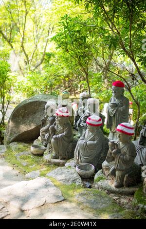 Statuen der ursprünglichen Anhänger Buddhas (Shaka Nyorai in Japan" genannt), mit gestrickten Mützen an Daisho-in Tempel (Daishoin Tempel), Miyajima, Japan. Stockfoto