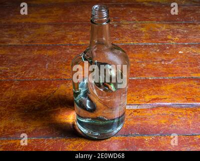 Glasflasche für Wodka mit einem Griff auf einem hölzernen Hintergrund. Hals einer Glasflasche. Alkohol. Gläser für Alkohol. Schlechte Gewohnheiten. Alkoholismus. Backgroun Stockfoto
