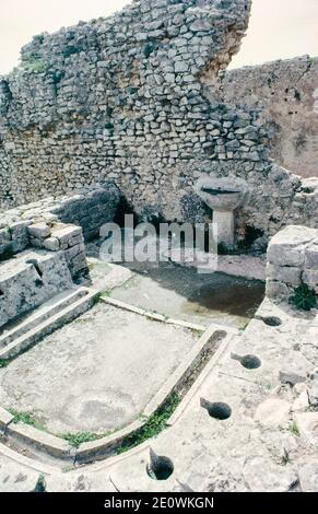 Dougga (Thugga) - Archäologische Stätte im Norden Tunesiens, Ruinen von Berber, punische und römische Siedlung, die am besten erhaltene römische Kleinstadt in Nordafrika. Latrinen und ein Handbecken. Archivscan von einem Dia. April 1976. Stockfoto