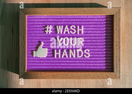 Waschen Sie Ihre Hände Hashtag Nachricht auf lila Plakatwand Hinweis im Geschäft gute Handhygiene für Coronavirus Prävention. Filzzeichen für soziale Medien Stockfoto