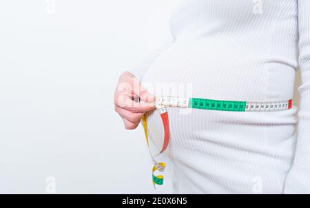 Schöner Körper der schwangeren Frau mit Maßband, um die Entwicklung des Babys zu überprüfen, weiß Hintergrundr, Gesundheit und Wellness. Gesundheit Wohlbefinden Pregnan Stockfoto