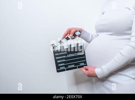 Schwangere Frau Hände mit Klappbrett auf ihrem Bauch. Mit Ladezeichen Stockfoto