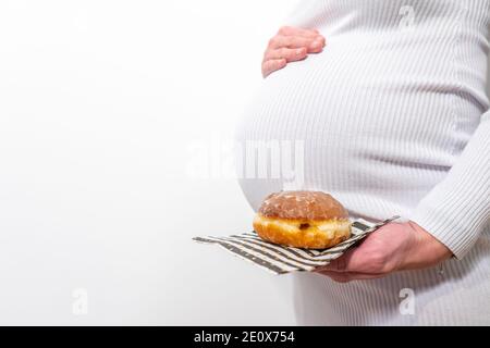 Schwangerschaft und ungesunde Ernährung Konzept: Schwangere Frau hält einen Teller mit leckeren Donuts in der Hand Stockfoto