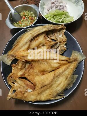 Gebratener Fisch mit würzigem Salat in gehackte frische Chilischoten, in Scheiben geschnittene Schalotten, grob gehackte Tälchen und gehackten Koriander geben. Stockfoto