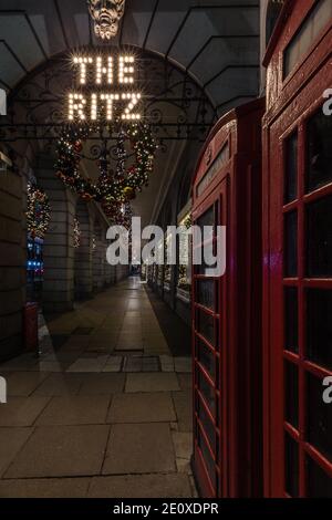 Das Ritz Hotel und die berühmten roten Telefonzellen in London während der Sperrzeit und der Weihnachtszeit. Stockfoto