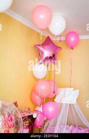 Das Bett des Mädchens in der Ecke des Zimmers ist mit Luftballons dekoriert. Stockfoto