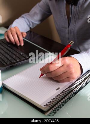 Weibliche Hände mit einem roten Stift schreiben auf Notebook. Selektiver Fokus Stockfoto