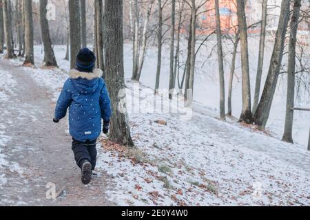 Junge geht auf einem Log. Handausgleich. Winterlandschaft im Wald. Aktivitäten im Winterwald. Weihnachtsfeiertage. Interessante Spiele im Winter Stockfoto