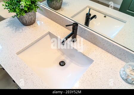 Blick von oben auf das Waschbecken und den schwarzen Wasserhahn, der am befestigt war Weiße Arbeitsplatte eines Badezimmers Stockfoto