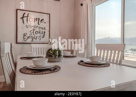 Weißer Tisch-Set für vier Personen im Esszimmer von Haus mit großem Fenster Stockfoto