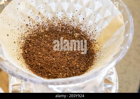 Die Makro-Nahaufnahme von Bio gemahlenen Kaffeebohnen in Papierfilter auf heißen Brüh Kaffee tropper für den Morgen Kaffee trinken. Stockfoto