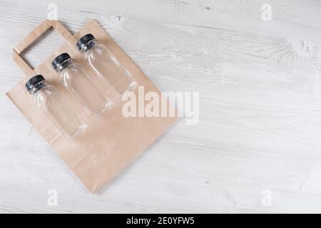 Mockup, Szene Schöpfer. Papiertüte, drei Plastikflaschen. Umweltfreundliche Lebensmittelverpackungen und Bio-Taschen aus Baumwolle auf grauem Hintergrund mit Kopierplatz Stockfoto