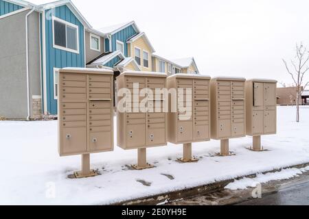 Reihe von Briefkästen auf der verschneiten Straße entlang einer nassen Nachbarschaftsstraße im Winter Stockfoto