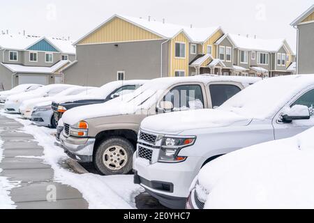 Autos auf dem Parkplatz einer Nachbarschaft gegen Häuser Und Ferienwohnungen im Winter Stockfoto
