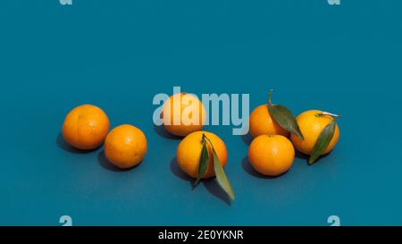 Clementinen Frucht mit grünen Blättern, Nahaufnahme. Minimalismus Fruchtkomposition mit Mandarinen und scharfen Schatten. Stockfoto