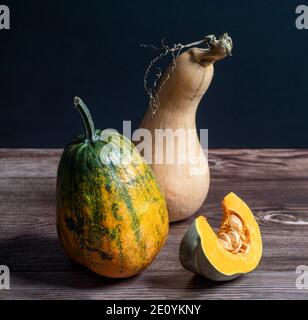 Reife Kürbisse auf Holztisch auf schwarzem Hintergrund, Nahaufnahme. Stockfoto