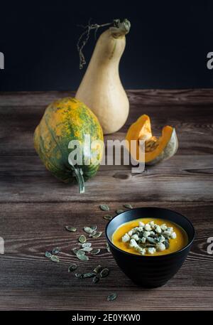 Kürbiscremesuppe mit blauem Käse und rohen Kürbissen auf Holztisch, Draufsicht. Stockfoto