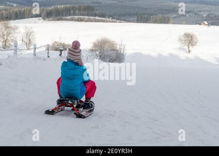 Kind auf Rodelschnee und Winterlandschaft. Rückansicht. Stockfoto