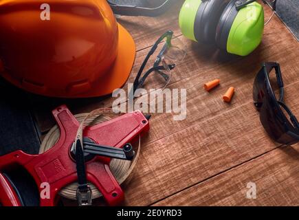 Technische Band messen Schutzhandschuhe Gehörschutz Helm auf Holzbrett. Stockfoto