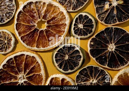 Getrocknete Zitrusscheiben von Limette, Grapefruit, Orange, Zitrone liegen auf einem gelben strukturierten Hintergrund. Draufsicht. Stockfoto