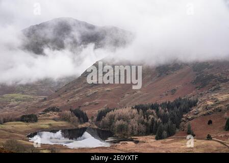 Schöne Landschaft Winter Sonnenaufgang Blick auf Blea Tarn von der Seite Pike in Lake District mit niedrigen Wolken über Berg Oberteile Stockfoto