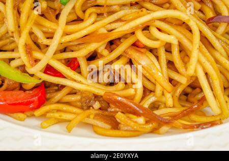 Nahaufnahme von Huhn Hakka Nudeln in einem weißen Teller mit Zugegeben Tomaten und anderes Gemüse Stockfoto