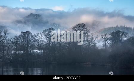 Episches Landschaftsbild mit Blick über Derwentwater im Lake District Catbells schneebedeckter Berg mit dichtem Nebel Rollen durch Tal Stockfoto