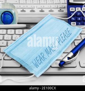 Gesichtsmaske und Bürohintergrund mit PC-Tastatur Stockfoto