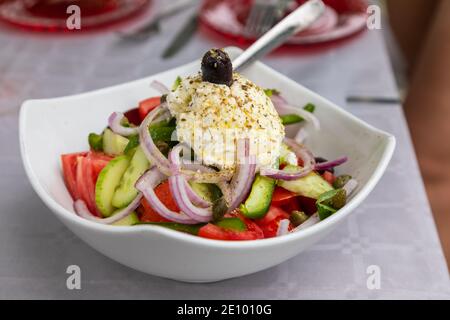 Gesunder griechischer Salat aus frischem Gemüse mit Tomaten, Pfeffer, Gurken, roten Zwiebeln, Oliven, Feta-Käse auf dem Tisch. Gesunde Ernährung, vegetar Stockfoto