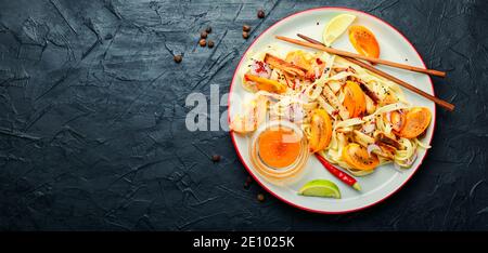 Asiatische Küche, Salat mit Nudeln, Kaki und Auberginen. Stockfoto