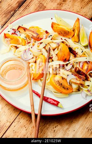 Asiatische Küche, Salat mit Nudeln, Kaki und Auberginen. Stockfoto