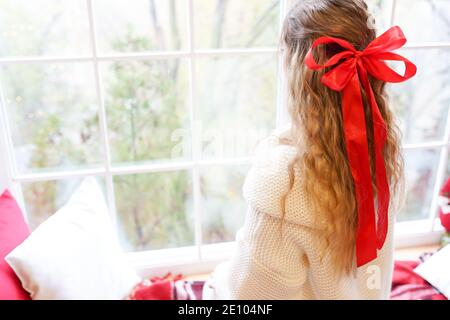 Junge schöne Frau sitzt zu Hause am Fenster tragen warm Pullover mit langen Haaren Stockfoto